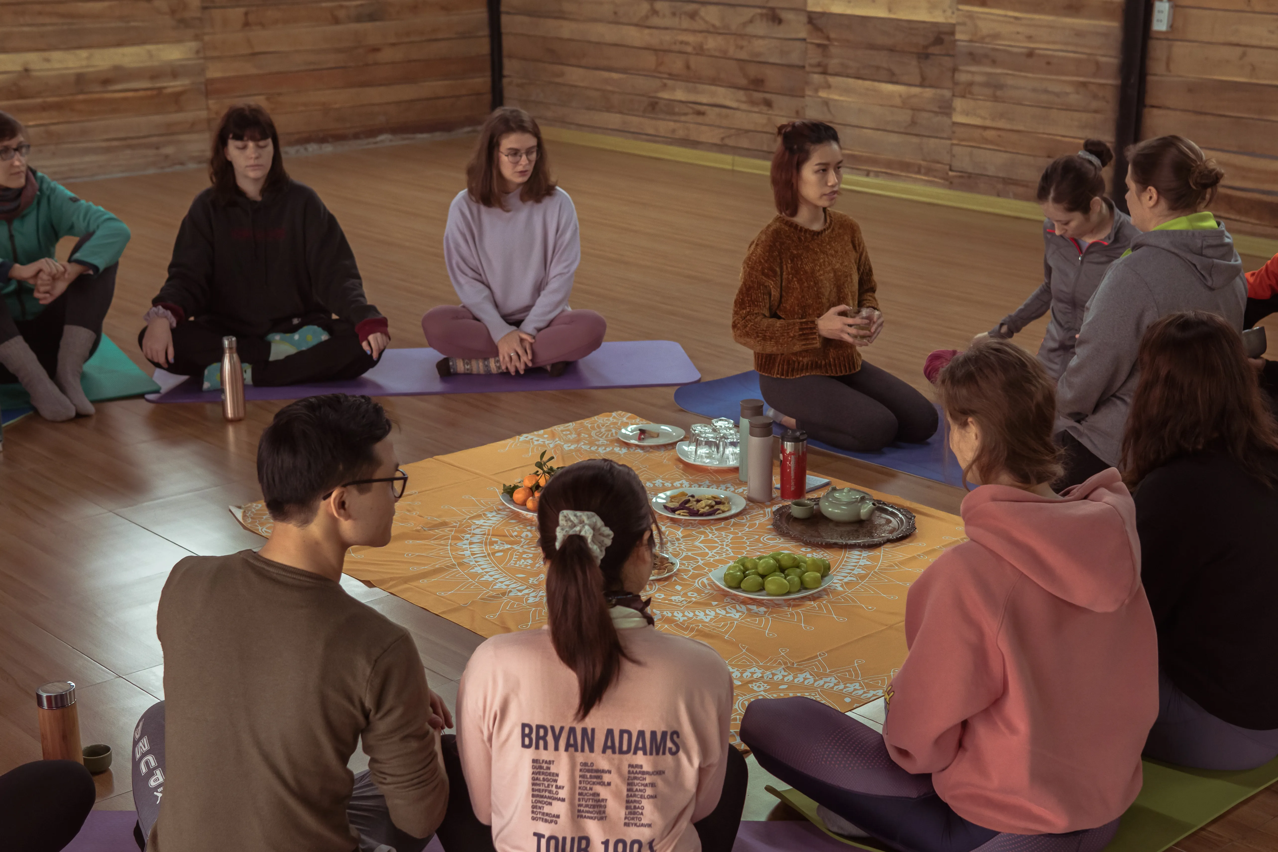 Mai sitting with a small group during a guided session, hands resting together
